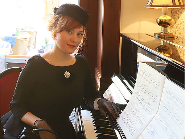 Solo-Pianistin Yuliya Drogalova lehnt an einem schwarzen Piano
